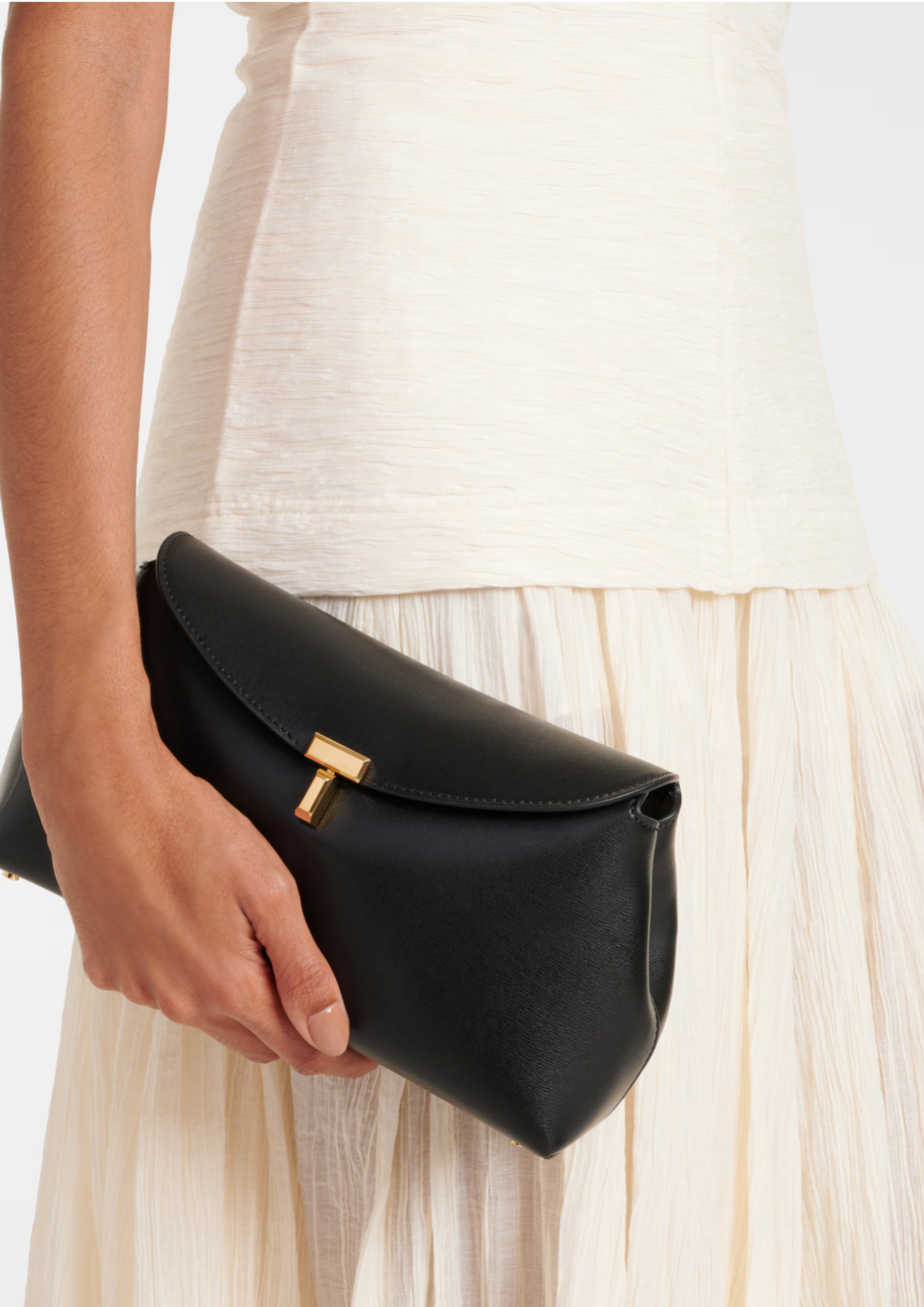 Toteme T-Lock Clutch nera in pelle liscia portata a mano
