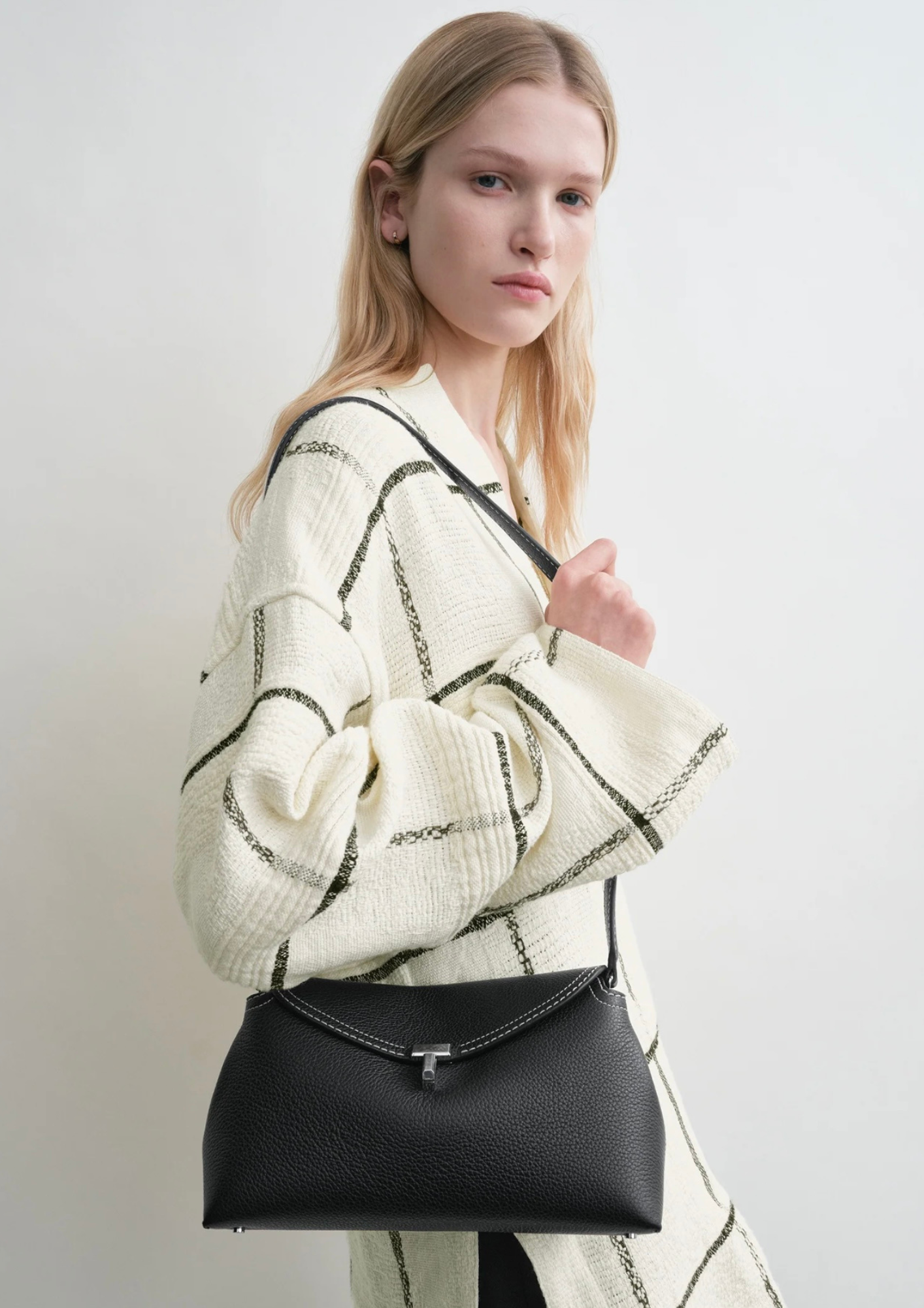 Toteme T-Lock Clutch nera indossata crossbody con tracolla
